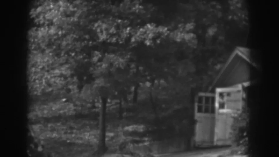 1938 Vineland, New Jersey home-movie still showing open shed doors below a leafy, sun-dappled hillside.