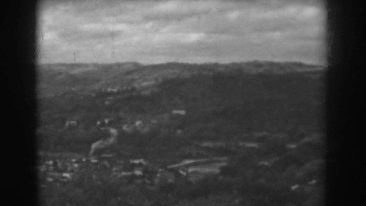 Distant hills and a small town seen through a dark 8mm film frame.