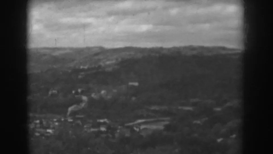 1938 Vineland, New Jersey home-movie frame showing soft distant hills, scattered buildings, and a cloudy sky.