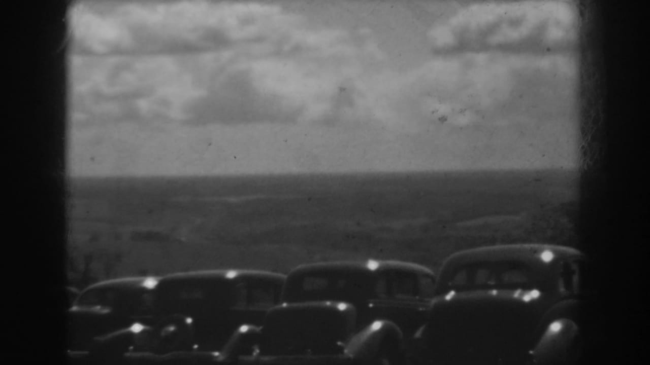 1938 West Virginia hilltop view with a line of parked automobiles in front of distant ridges and a cloudy sky.