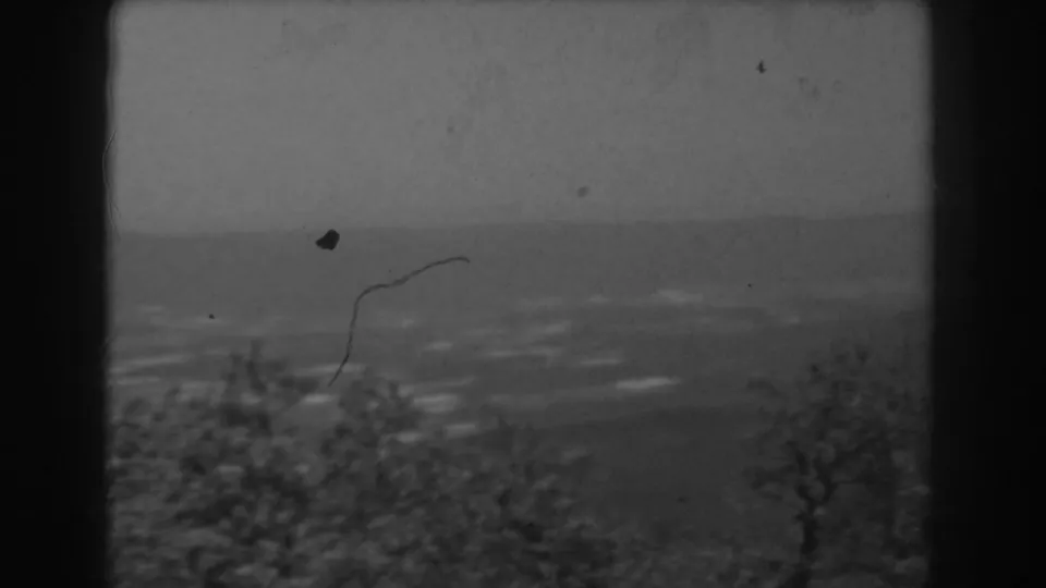 Late-1930s West Virginia home-movie frame of a hazy valley and treetops, marked by grain, dust, and dark window framing.