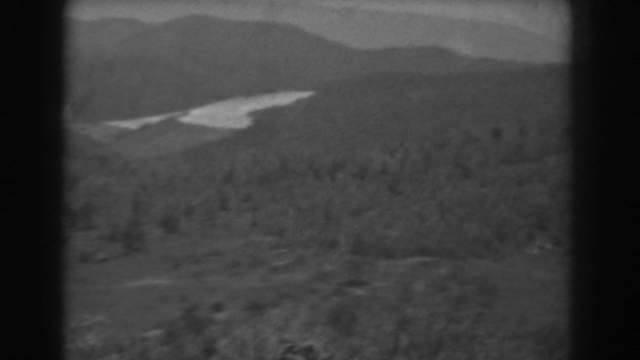 Wooded valley and distant hills with a bright winding waterway near the ridge line.