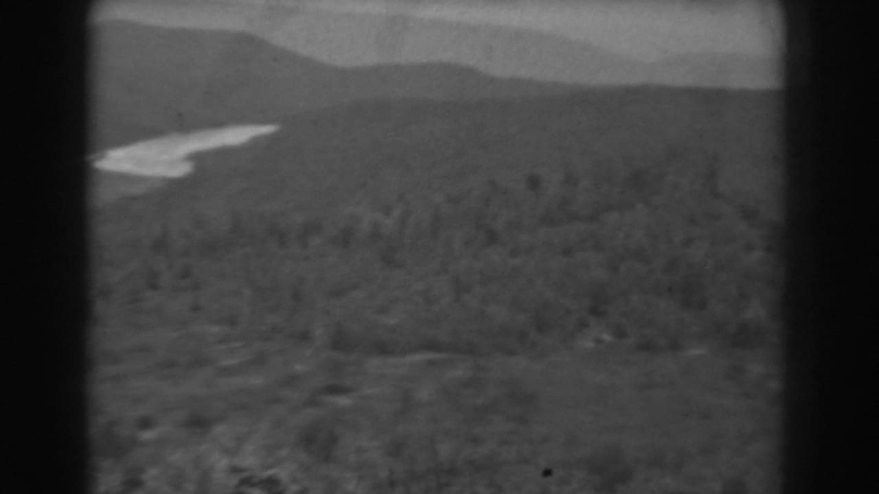 1938 West Virginia 8mm frame of forested slopes and ridges, with the pale waterway partly visible at left.