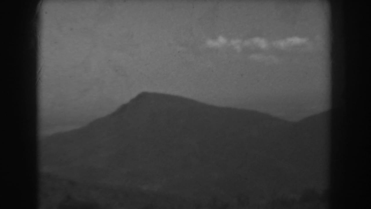 1938 West Virginia 8mm frame with a darker mountain profile and small clouds crossing the upper sky.