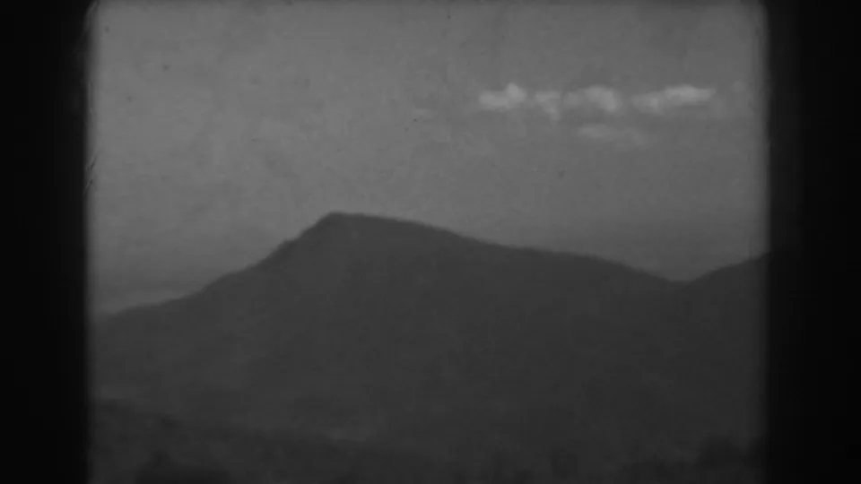 1938 West Virginia 8mm frame with a darker mountain profile and small clouds crossing the upper sky.