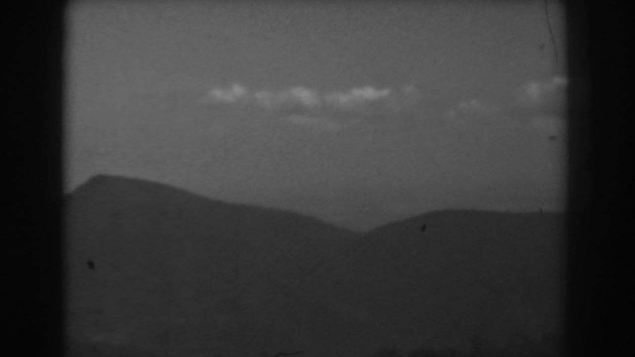 West Virginia mountain skyline in black and white, with scattered clouds and a faint vertical film artifact.