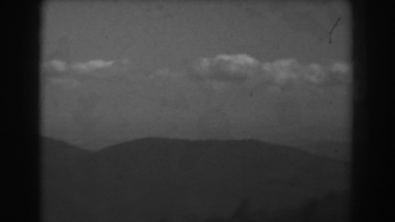 Black-and-white 1938 West Virginia frame with layered mountain silhouettes below a bright line of clouds.