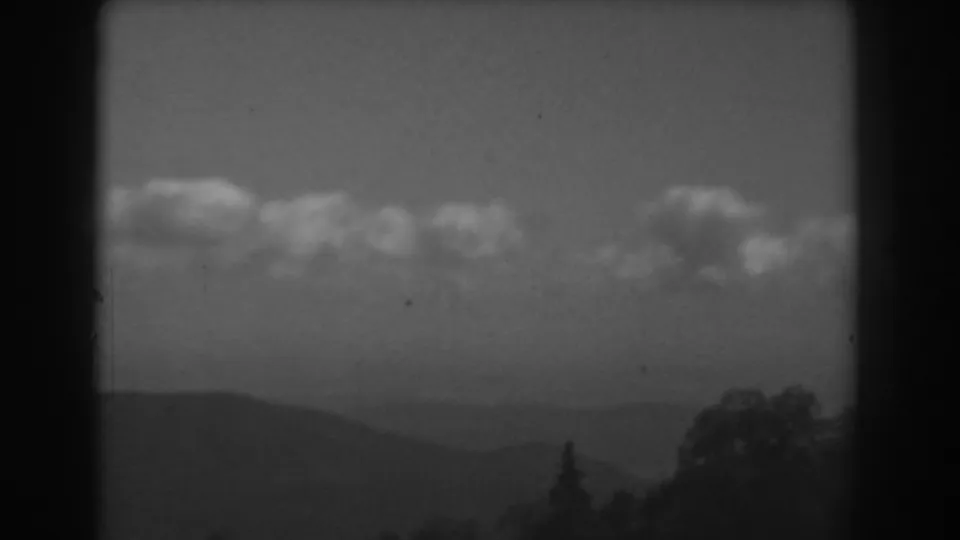 Black-and-white 1938 West Virginia frame showing a hazy mountain valley, cloud band, and dark trees along the lower edge.