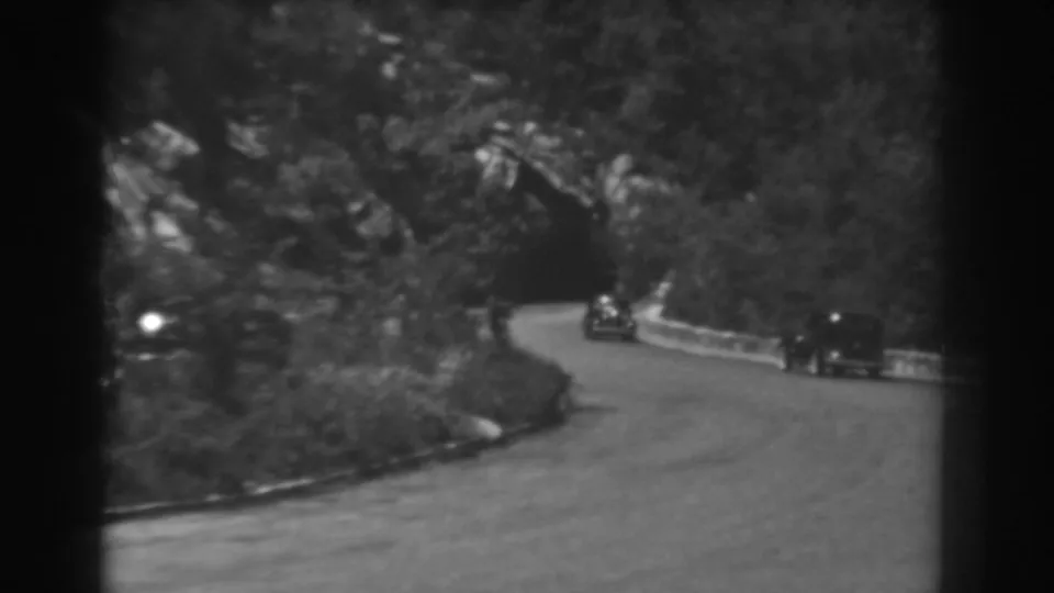 1938 West Virginia home-movie view of classic cars on a wooded curving road.