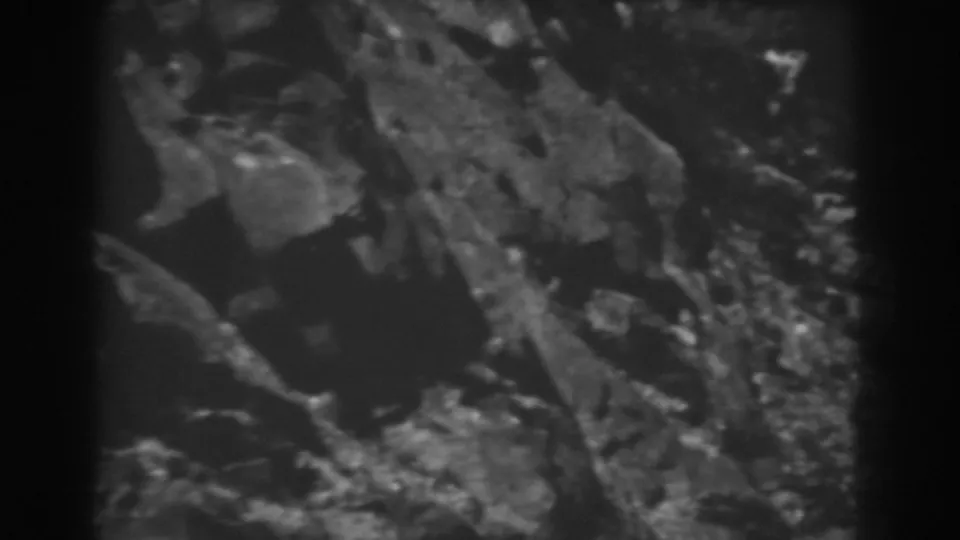 1938 West Virginia home-movie view of a rocky slope with dark shadows and scattered scrub plants.