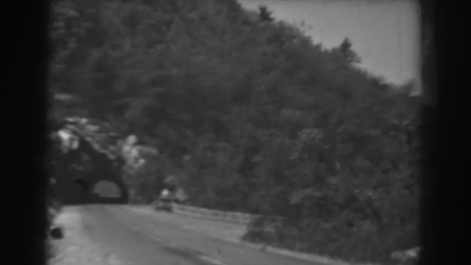 1938 West Virginia 8mm frame showing a road curving toward a tunnel beneath forested slopes.