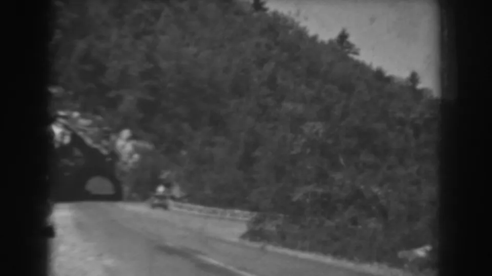 1938 West Virginia 8mm frame with a small car near a tunnel on a winding mountain road.