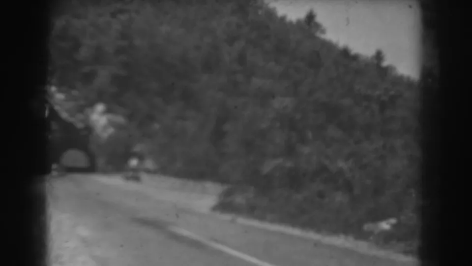Soft 8mm frame from 1938 West Virginia showing the car farther from the tunnel on a sunlit mountain road.