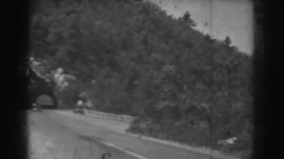 The car continues away from the tunnel on a curving West Virginia mountain road, framed by 8mm film borders.