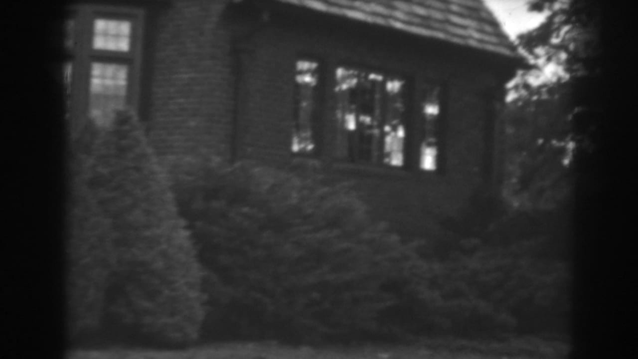 1938 Winchester, Maryland frame of the same brick residence, with divided-light windows above clipped shrubs.