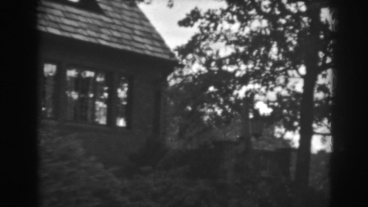 1938 Winchester, Maryland home-movie frame showing a house corner, shingled roof, windows, trees, and soft black-and-white film edges.