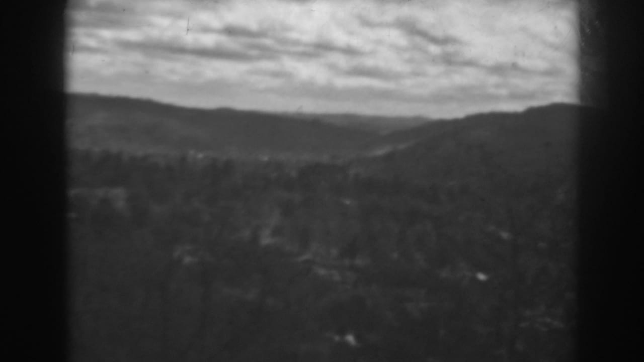 Distant ridges and a cloudy sky over a dark, wooded foreground.