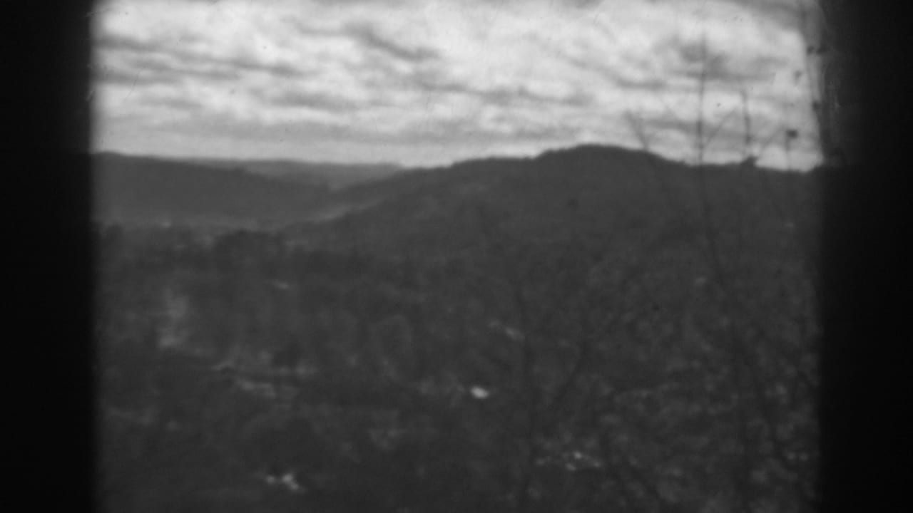 1938 Winchester, Maryland home-movie frame showing distant hills, a wooded valley, bare branches, and dark window divisions.