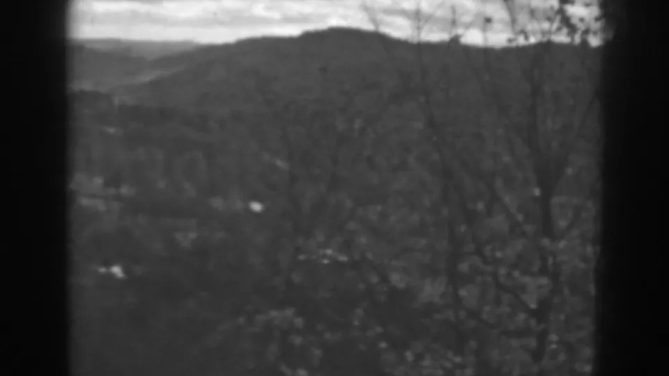 Winchester, Maryland 1938 landscape frame showing a hill ridge, leafless branches, cloudy sky, and dark window edges.