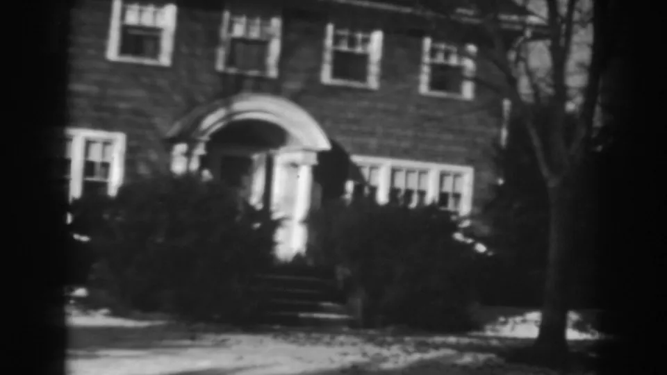 1938 Winchester, Maryland frame of a brick residential exterior with an arched entry, front steps, bare tree, shrubs, and light snow.