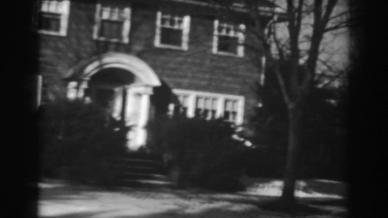 Brick house entrance with arched doorway, windows, bare trees, and snow along the ground.