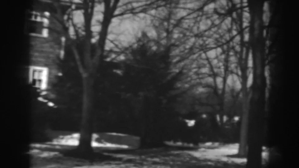 1938 Winchester, Maryland frame ending on bare trees, shrubs, snow patches, and the edge of the brick house.