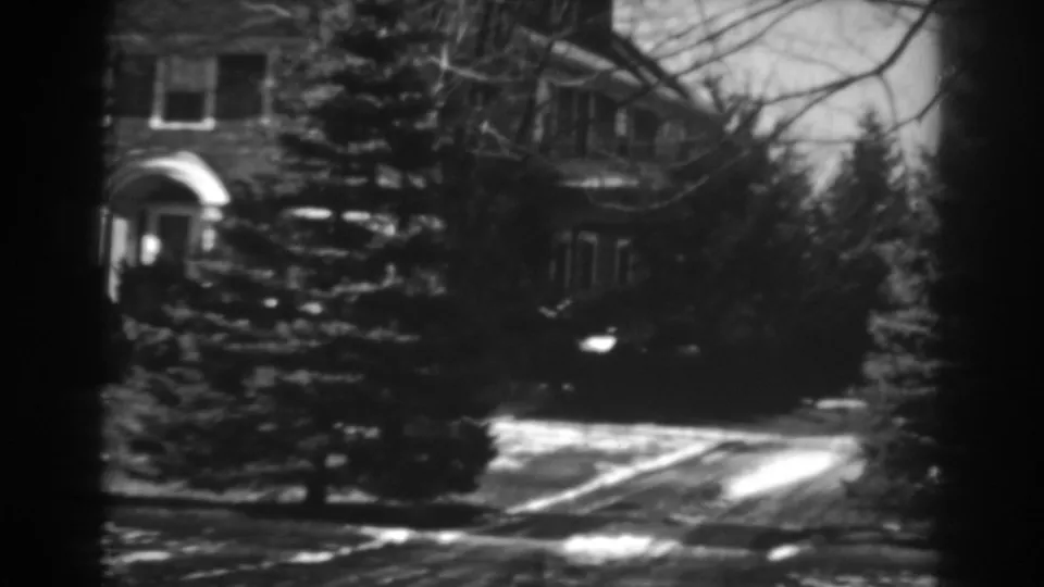 A Winchester, Maryland residential exterior appears behind pine trees, with a driveway showing melting snow in the 1938 footage.