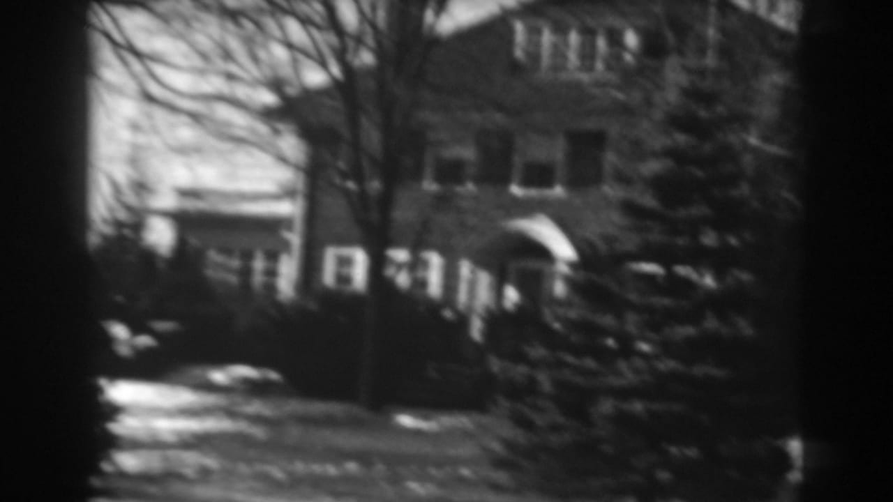1938 Winchester, Maryland home-movie frame showing a two-story house, arched entry, bare trees, and snow patches in the yard.