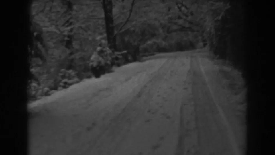 1938 Winchester, Maryland 8mm frame showing a snowy dirt road with tire tracks, wooded edges, and bare trees.