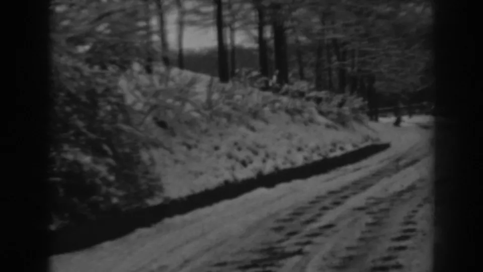 End frame from a 1938 8mm winter road scene near Winchester, Maryland, showing tire tracks, snow banks, and a wooded roadside.