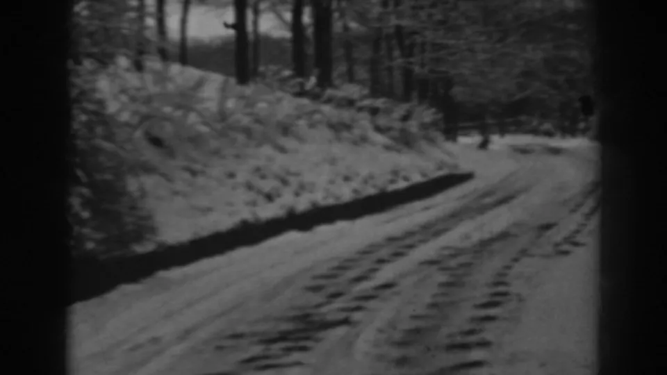 Final frame shows the snowy wooded road curving ahead, with tire tracks visible in the 1938 Maryland home movie.