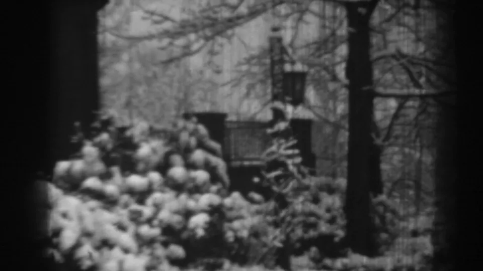 1938 Winchester, Maryland yard scene with snow-laden bushes, brick gateposts, iron fencing, and a large house in the background.