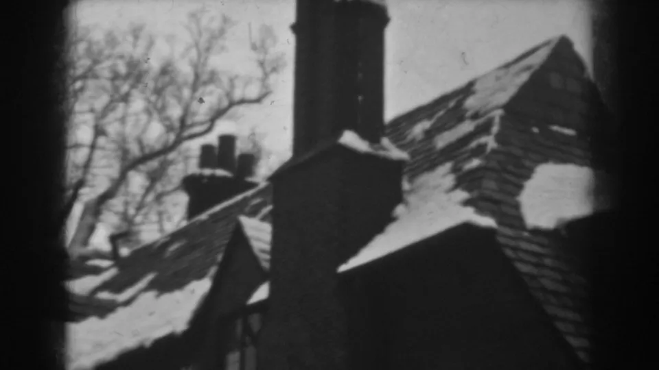 A 1938 Winchester, Maryland winter view of a house roof, chimney, and leafless trees captured on 8mm film.