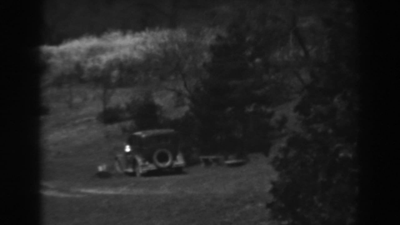 A 1930s automobile appears parked on a grassy hillside near trees in Winchester, Maryland home-movie footage.