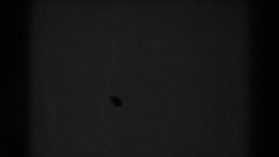 The 1938 8mm frame has faded into near darkness, leaving faint film texture and a small speck visible.