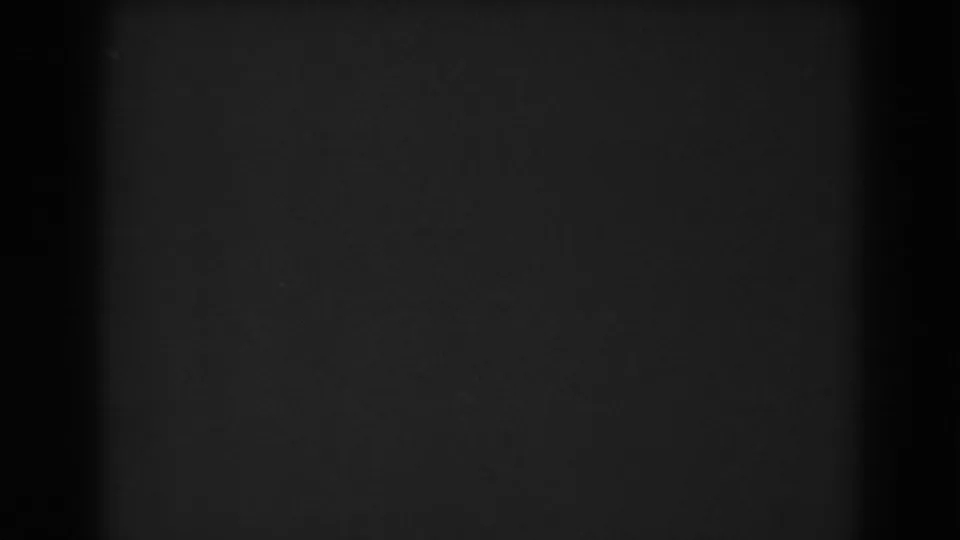 Near-dark 8mm frame from the Winchester clip, showing only subdued grain, slight tonal variation, and edge shadow.