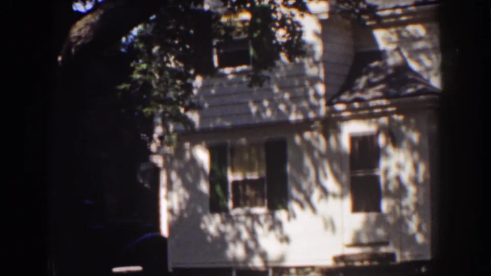 Home-movie frame from Mount Washington in 1939 showing the clapboard exterior under heavy tree shade.