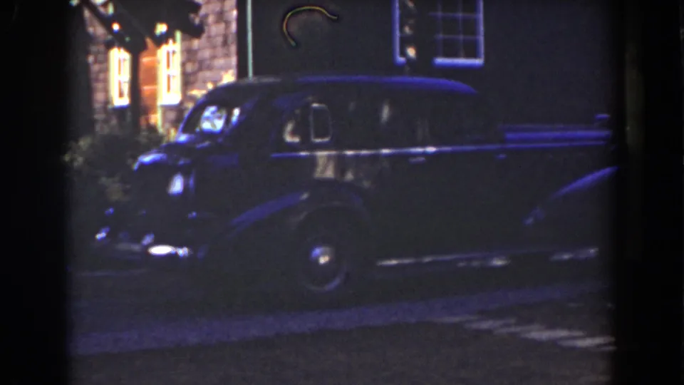 Dark sedan parked by a Mount Washington house exterior, with warm light visible through upper windows.