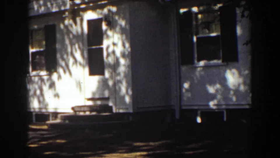 White house exterior in Mount Washington with a doorway, shuttered windows and dappled daylight shadows.