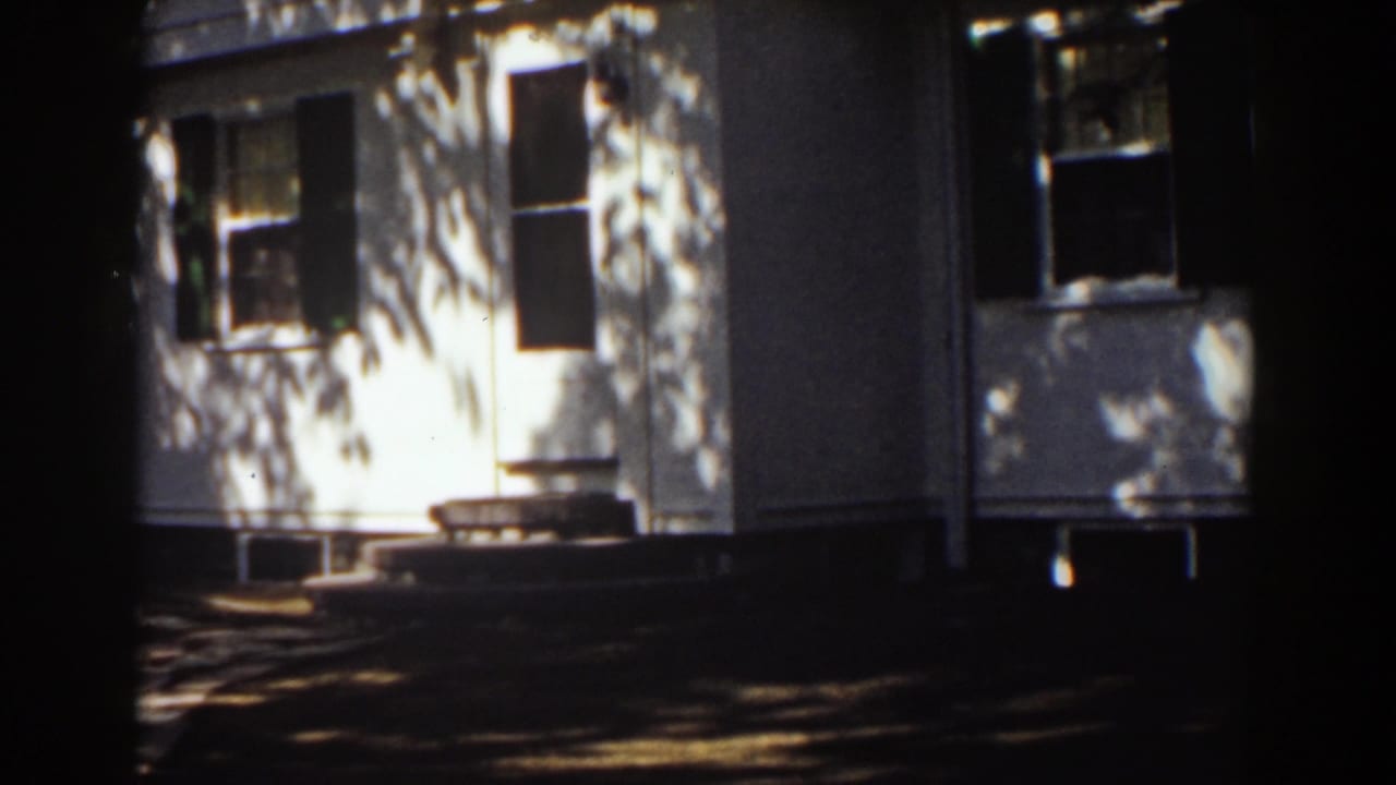 White two-story house exterior with dark shutters and tree shadows.