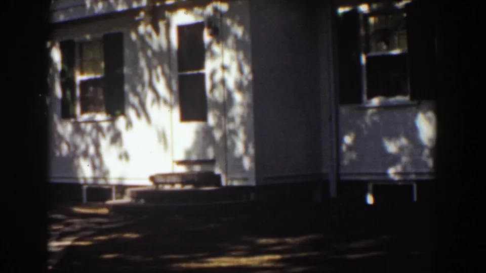 1939 Mount Washington, New Hampshire home-movie frame showing a white clapboard house with dark shutters in dappled sunlight.