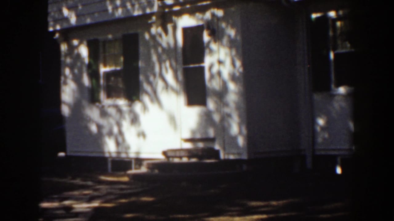 House facade with windows, shutters, and sunlit wall sections.