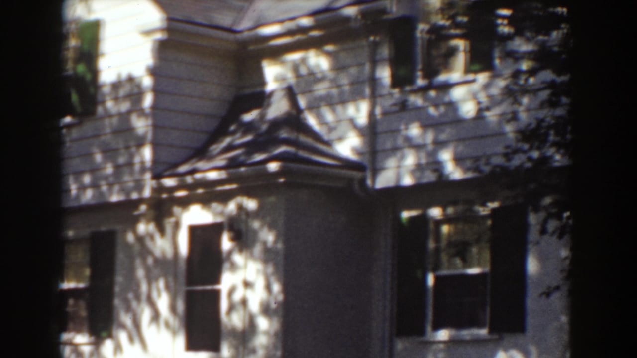 White house facade with dormer-like roof detail and dark shutters.