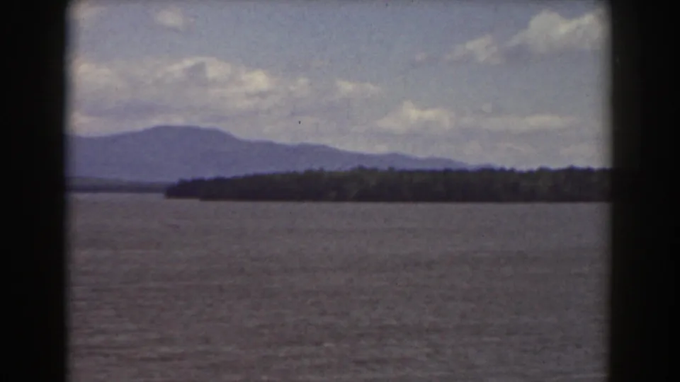 1939 8mm view near Mount Washington, New Hampshire, showing open water, a wooded shoreline, and hazy mountain ridges.