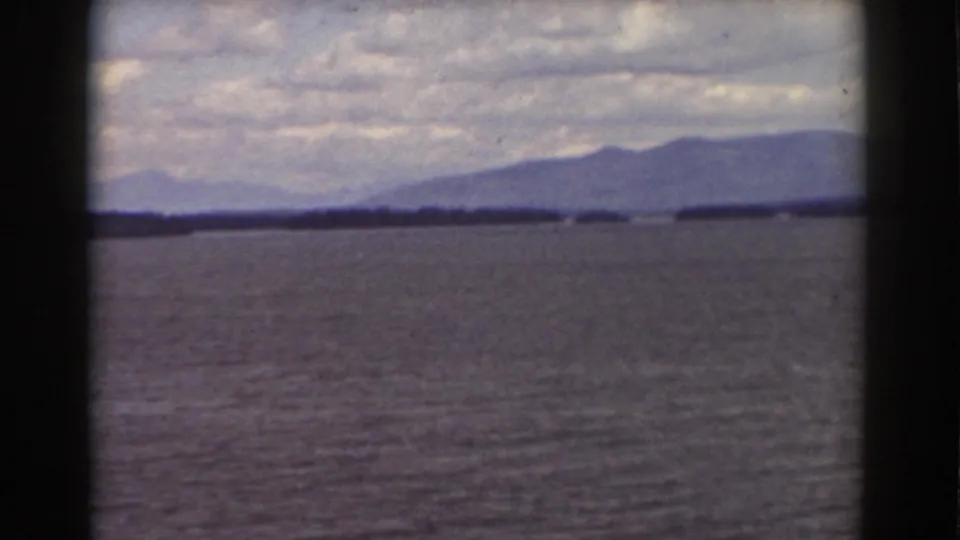 Mount Washington-area 8mm frame showing open water, a dark shoreline, and blue-gray mountains in the distance.