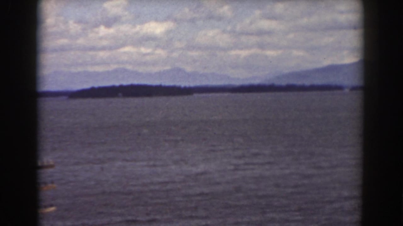 1939 8mm view near Mount Washington showing lake water, distant wooded shore, mountains, and dark window framing.