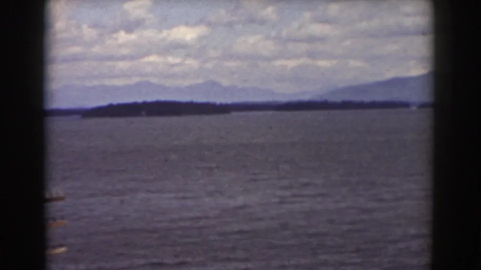1939 8mm view near Mount Washington showing lake water, distant wooded shore, mountains, and dark window framing.