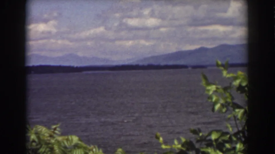 1939 8mm landscape view near Mount Washington, with rippled lake water, distant mountains, clouds, and foreground greenery.