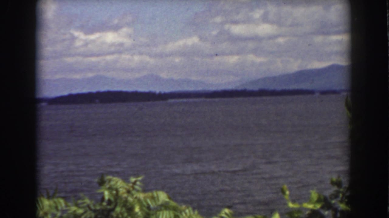 A final 1939 8mm frame holds on lake water and layered mountain ridges near Mount Washington, with leaves in the foreground.