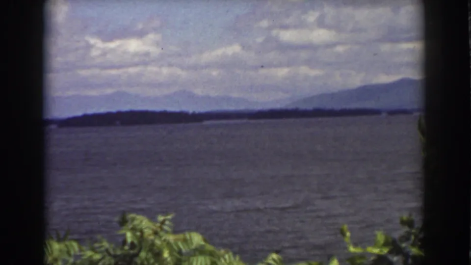 A final 1939 8mm frame holds on lake water and layered mountain ridges near Mount Washington, with leaves in the foreground.